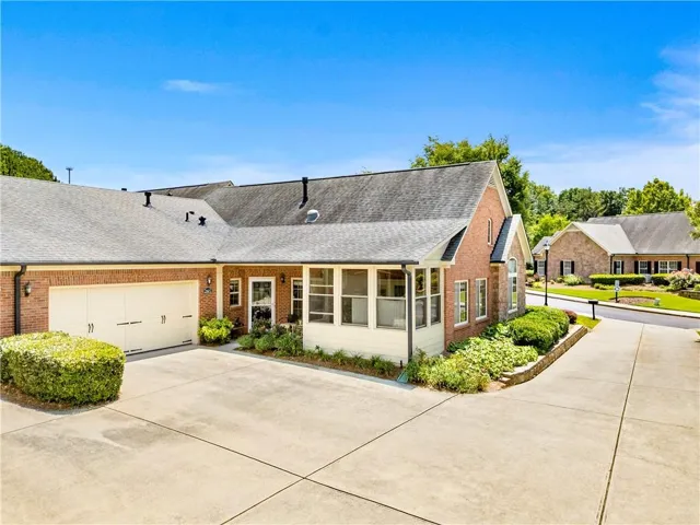 Brick exterior with a screened porch, two-car garage, concrete driveway, and established landscaping