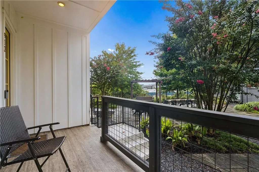 Private outdoor balcony with wood-finish flooring and a black metal railing
