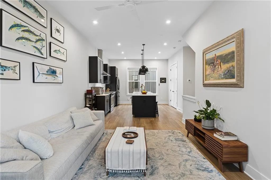 Open-concept living space featuring wood-finish flooring, recessed lighting, a ceiling fan, and a kitchen with dark cabinetry and an island