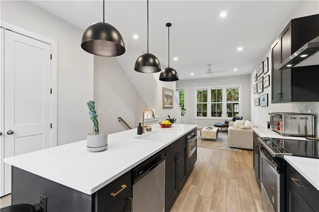 Modern kitchen featuring an expansive island with white countertops, dark cabinetry, and integrated appliances
