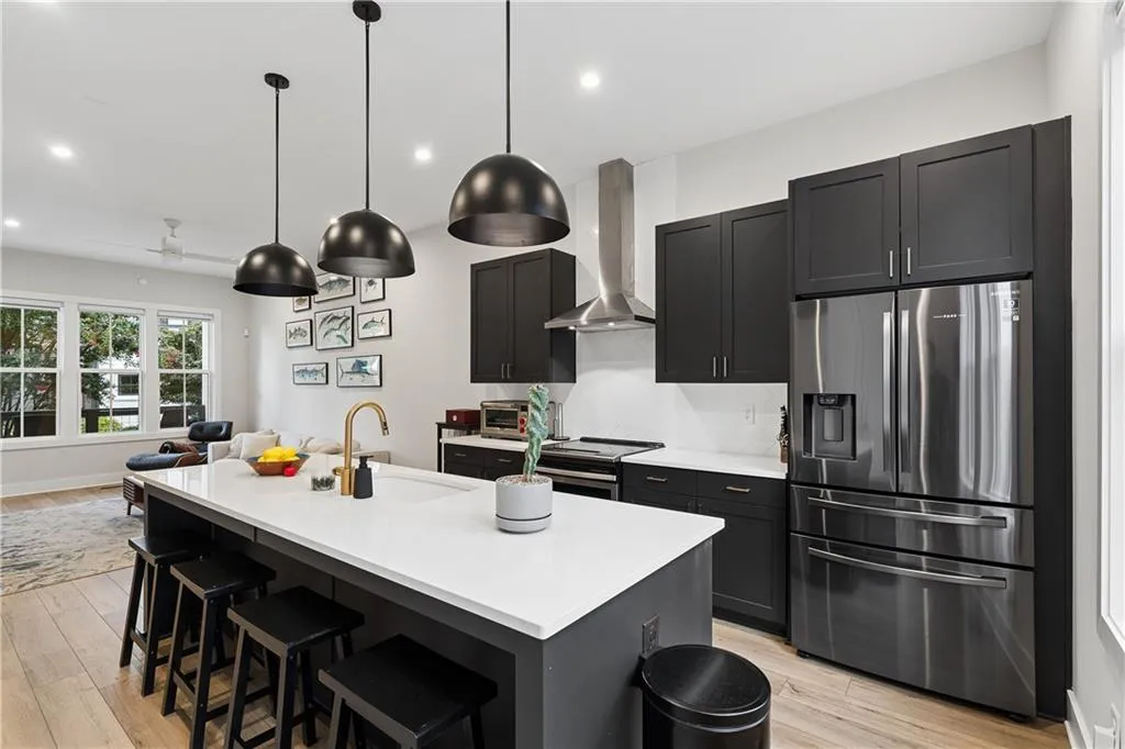 Open-concept kitchen featuring an oversized island with seating, dark shaker-style cabinetry, and stainless steel appliances