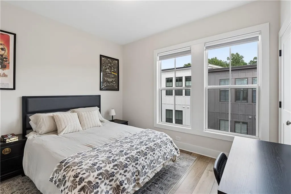 Bedroom featuring light wood-finish flooring and two large windows with white trim