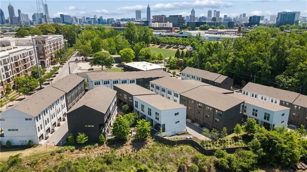 Modern townhome community featuring multi-level residences with contrasting light and dark facades, individual garages, and visible city skyline