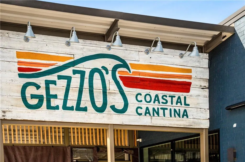 Painted wood panel signage under a metal awning with gooseneck lighting fixtures