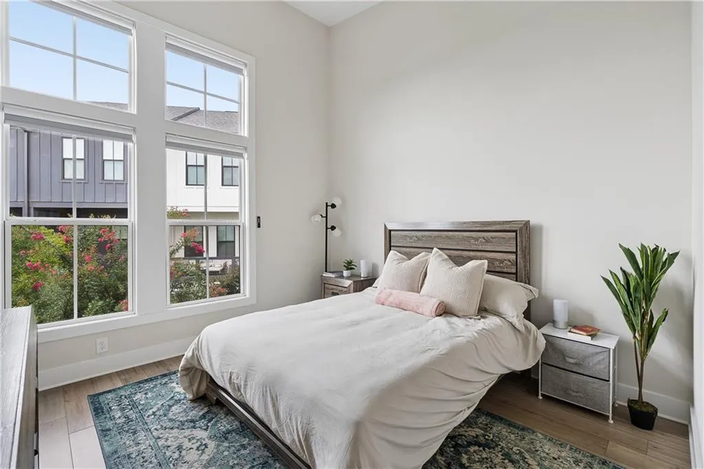 Bedroom featuring expansive multi-pane windows, wood-finish flooring, and light neutral wall finishes