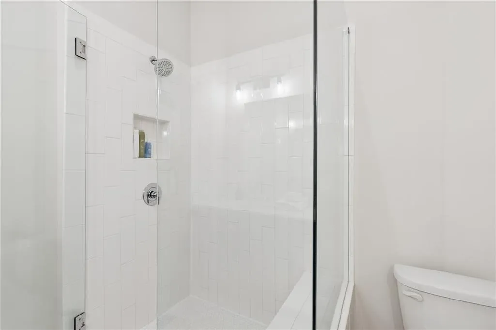 Glass-enclosed shower featuring white subway tile, a built-in niche, chrome fixtures, and a hex-tile shower floor