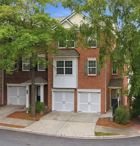 Brick exterior with multiple garages, a bay window, and gabled rooflines