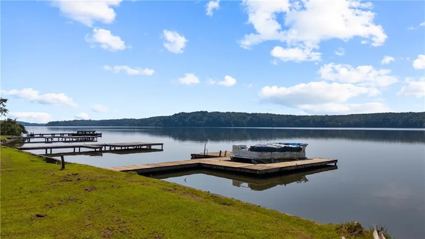 Dock featuring a water view, a forest view, and a lawn