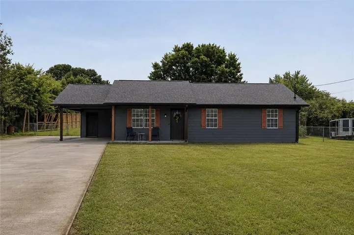 Single-story residence featuring charcoal gray siding, a dark shingle roof, and a covered carport