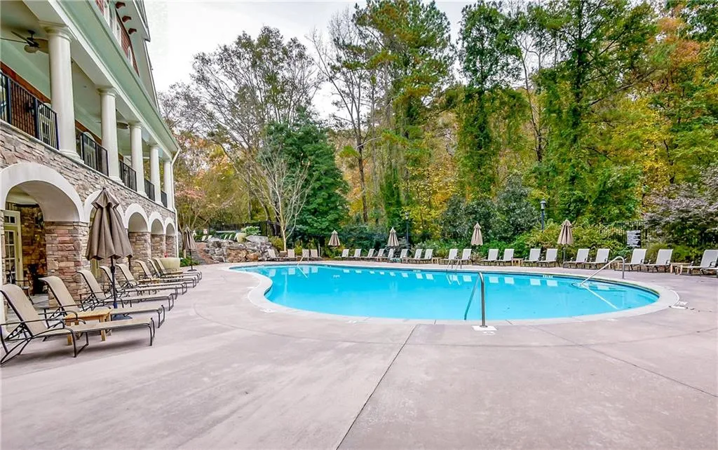 Community pool featuring a patio and view of wooded area