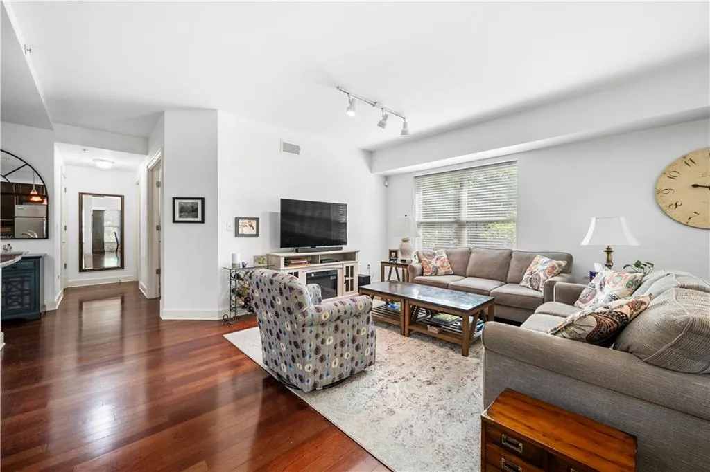 Living room with dark wood-style floors, track lighting, and baseboards
