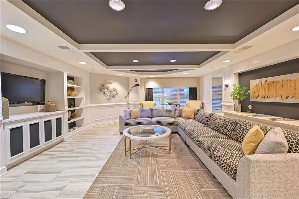 Living room with a decorative wall, built in shelves, recessed lighting, and a wainscoted wall