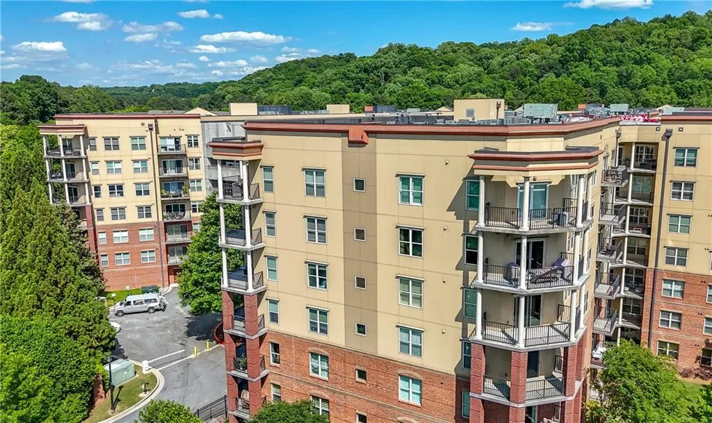 View of apartment building / complex with uncovered parking and a wooded view