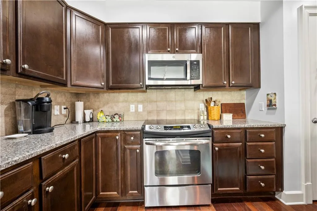 Kitchen with stainless steel appliances, dark brown cabinets, and light stone counters