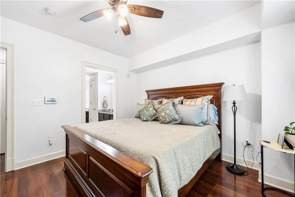 Bedroom featuring baseboards, dark wood-style floors, a ceiling fan, and ensuite bathroom