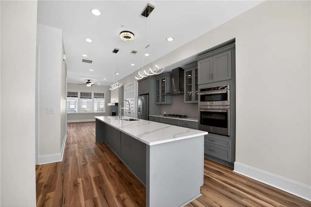 Kitchen featuring gray cabinetry, a spacious island, glass fronted cabinets, and pendant lighting