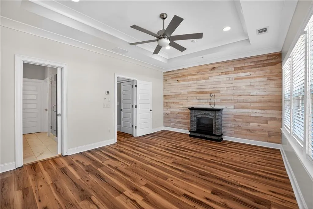 Unfurnished living room featuring a ceiling fan, wooden walls, wood finished floors, a fireplace, and recessed lighting
