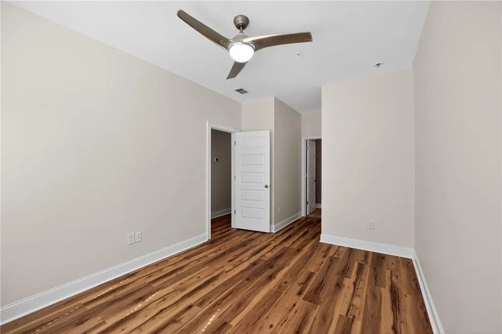 Empty room with dark wood finished floors and a ceiling fan