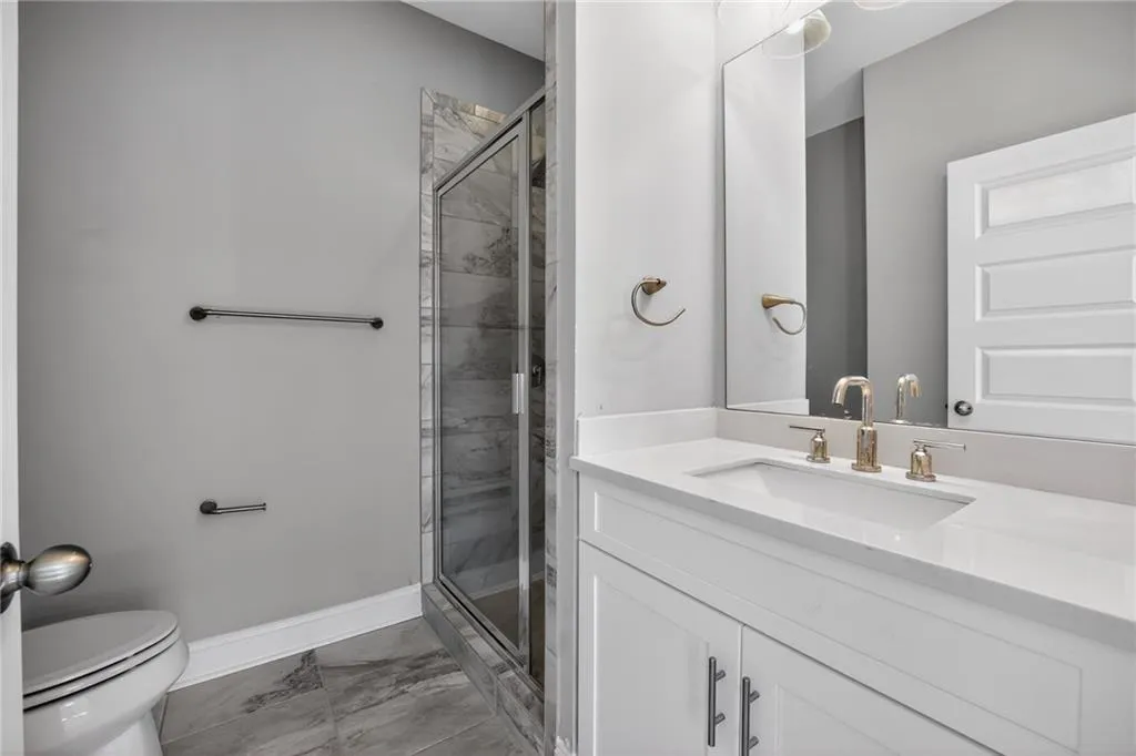 Full bath featuring vanity, a shower stall, and light marble finish flooring