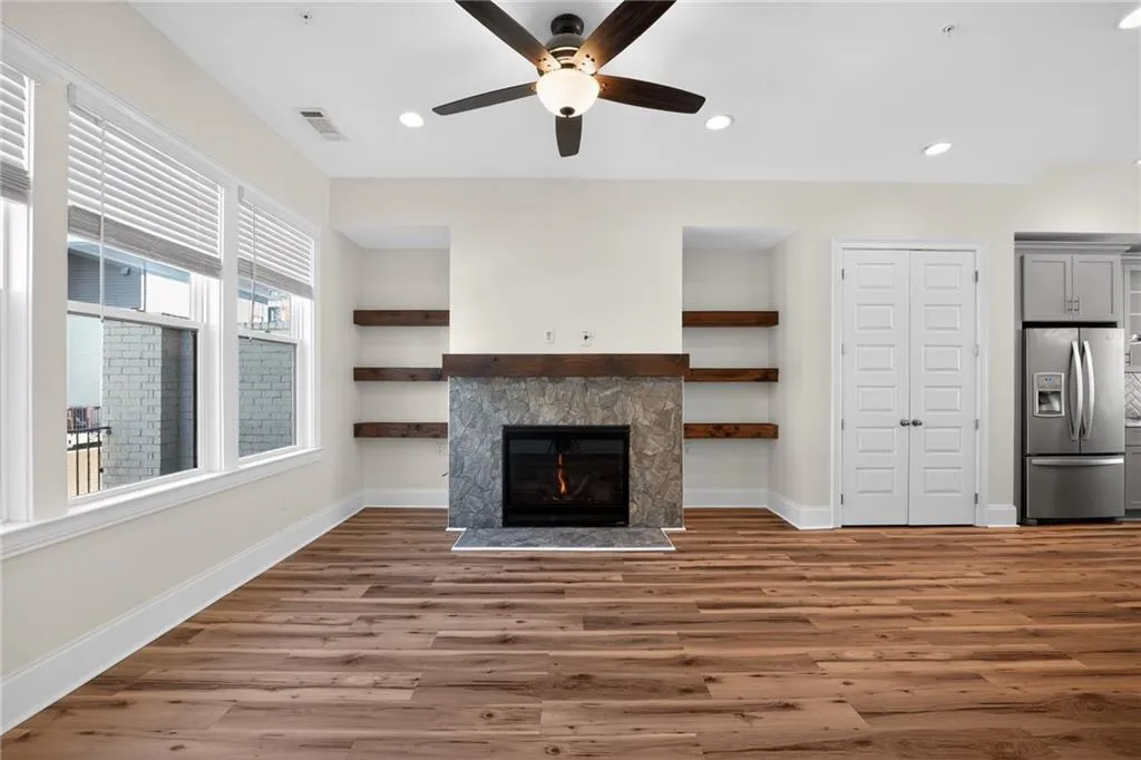 Unfurnished living room featuring a lit fireplace, dark wood-style floors, recessed lighting, and a ceiling fan