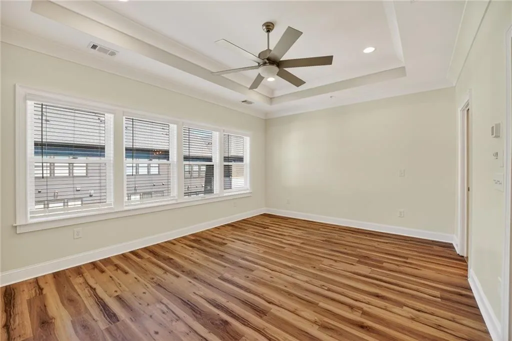 Empty room with ornamental molding, a ceiling fan, wood finished floors, a raised ceiling, and recessed lighting