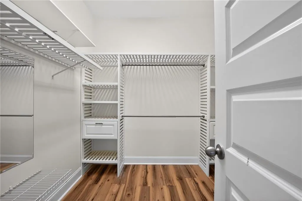 Walk in closet with dark wood-style flooring