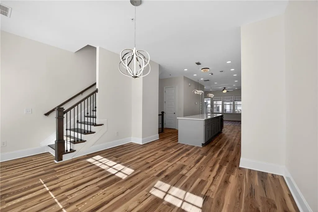 Unfurnished dining area with suspended lighting and dark wood-style flooring