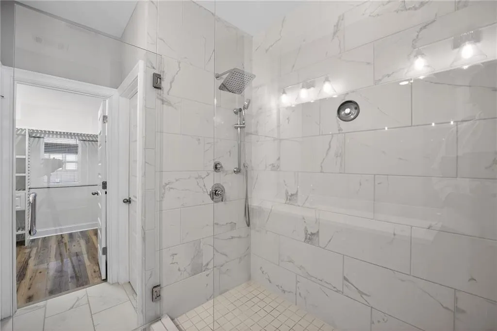 Bathroom with a stall shower, light marble finish floors, and a spacious closet