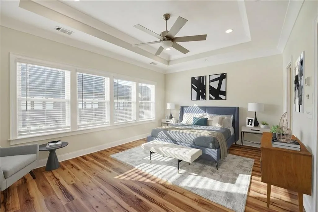 Bedroom with light wood finished floors, a ceiling fan, crown molding, a raised ceiling, and recessed lighting