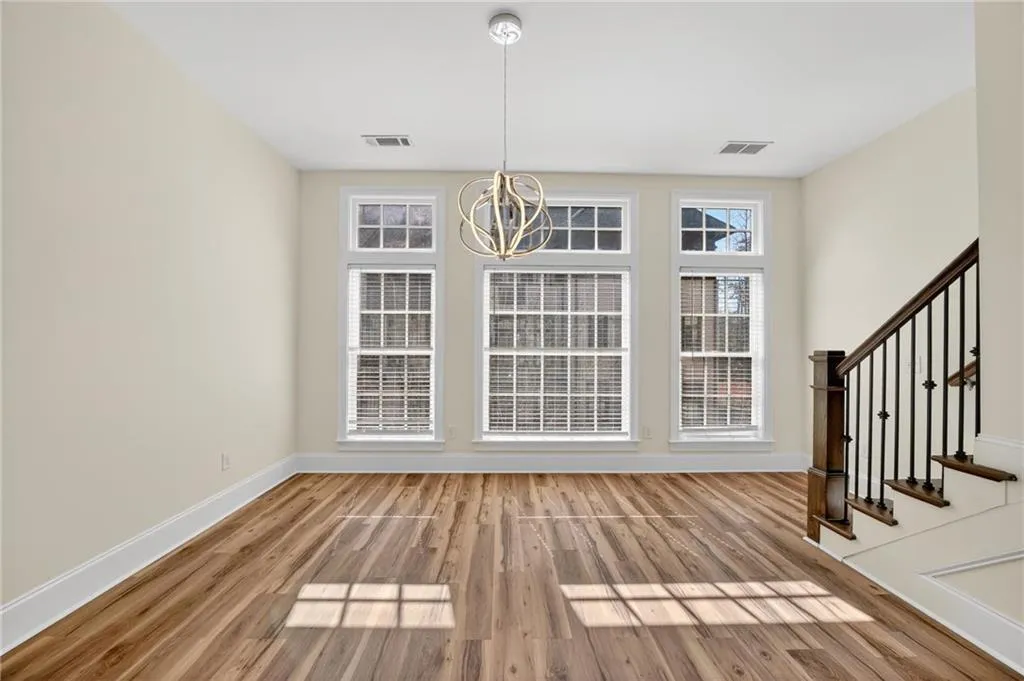 Unfurnished dining area with light wood-style flooring, hanging lights, and plenty of natural light