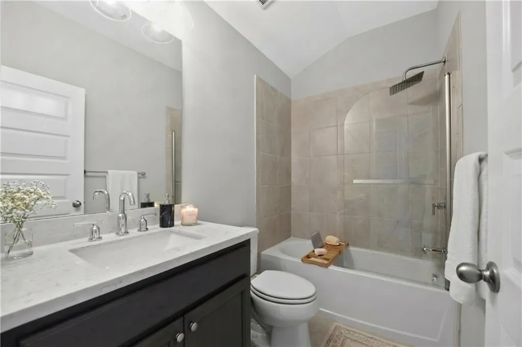 Full bath featuring vanity, vaulted ceiling, and shower / tub combination