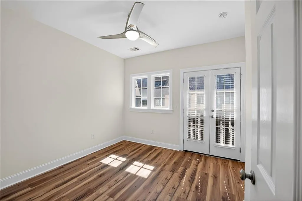 Empty room with french doors, ceiling fan, and dark wood finished floors