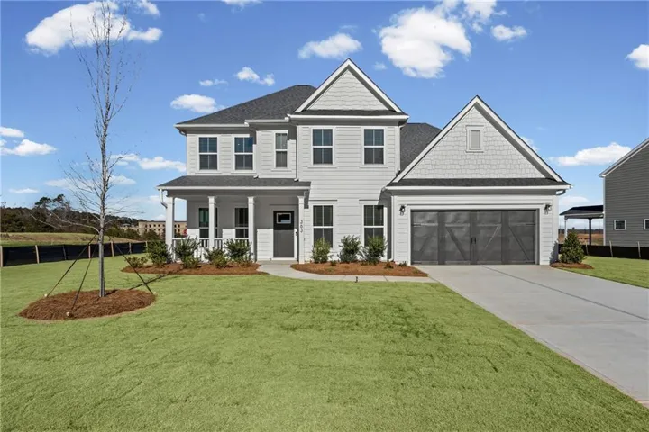 Two-story residence featuring light gray siding, dark gray garage doors, a covered front porch with white columns, a concrete driveway, and a manicured lawn