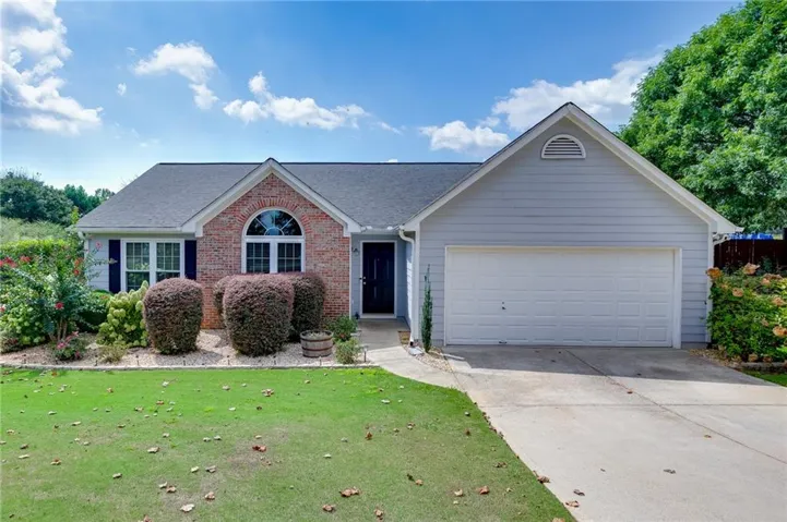 Brick and siding exterior featuring a prominent arched window, attached two-car garage, and a concrete driveway