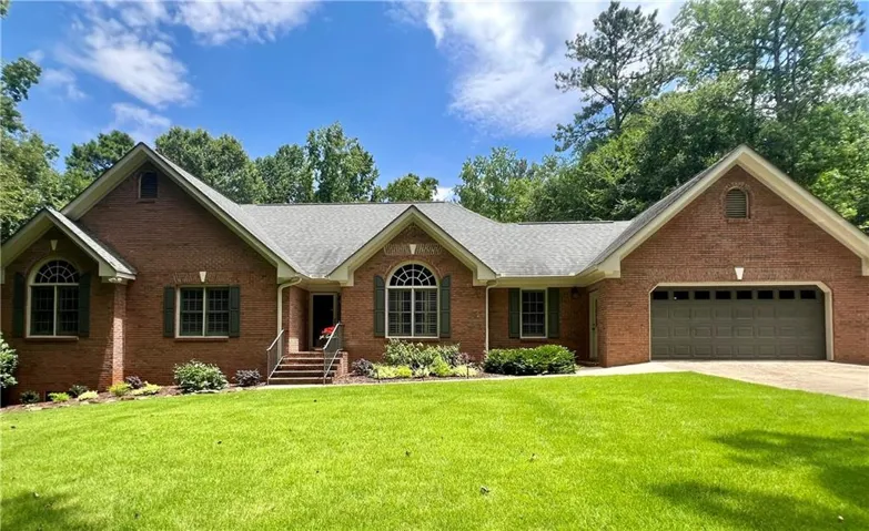 Brick exterior featuring an integrated two-car garage, arched windows, dark shutters, and a covered entry with steps