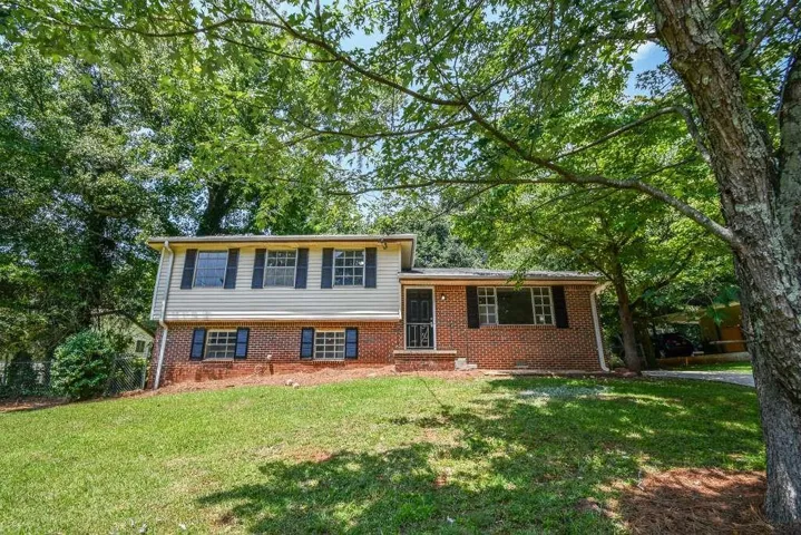 Brick and siding exterior with dark shutters, front door with security screen, and a paved driveway