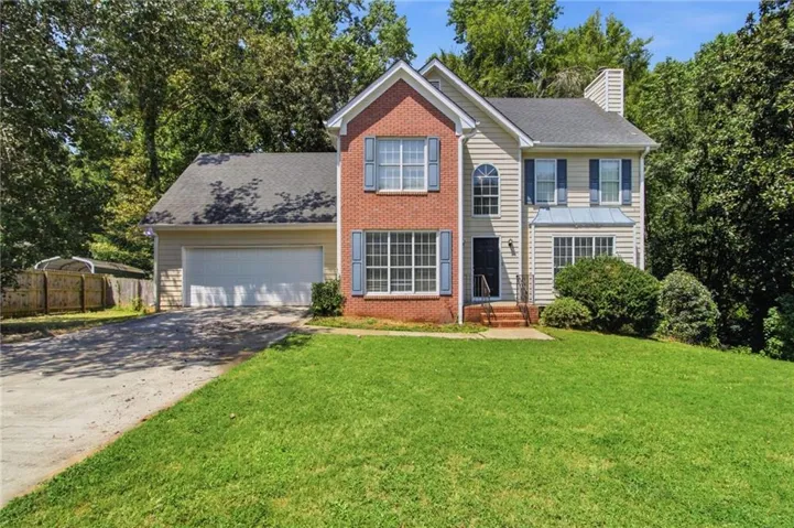 Two-story residence featuring brick and siding facade, an arched window, attached two-car garage, and a front entry porch with steps