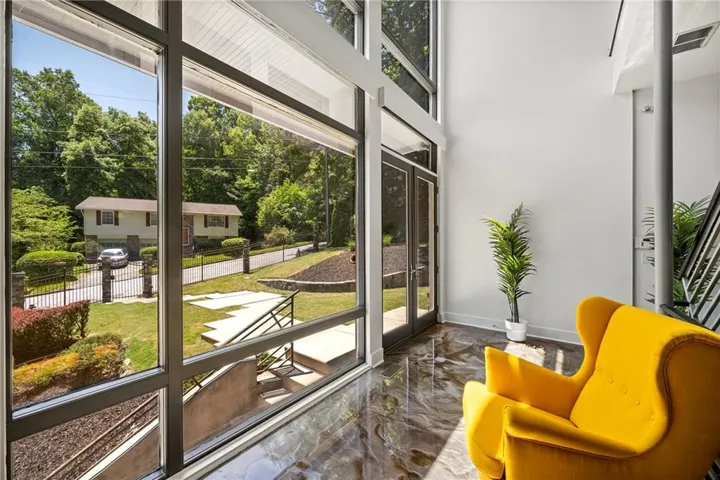 Two-story window wall, glass French doors, polished concrete flooring, white walls, and a visible metal staircase