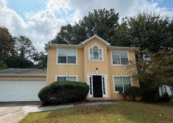 Stucco exterior, white window trim, arched window feature, dark entry door, attached garage
