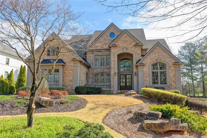 French country style house with brick siding, french doors, roof with shingles, and a front lawn
