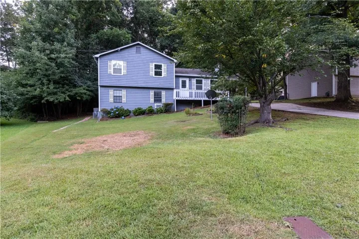Split-level residence featuring blue siding, white trim, and a white front porch