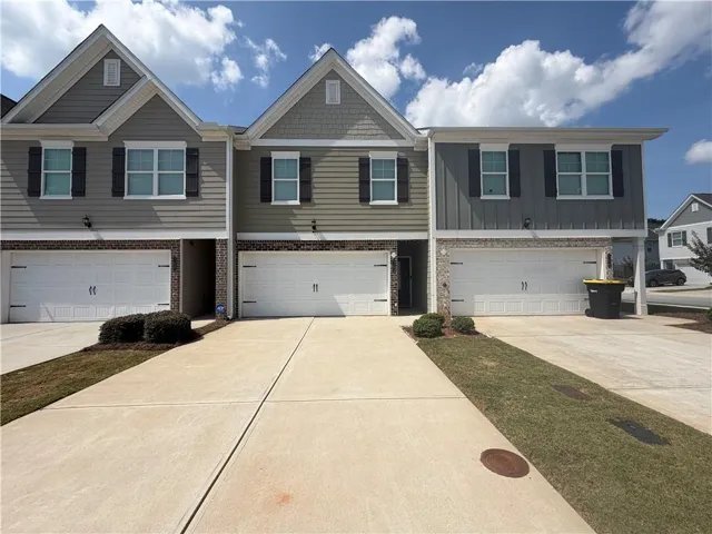 Multi-story exterior with a combination of lap siding and shake siding, featuring multiple garage doors and a concrete driveway