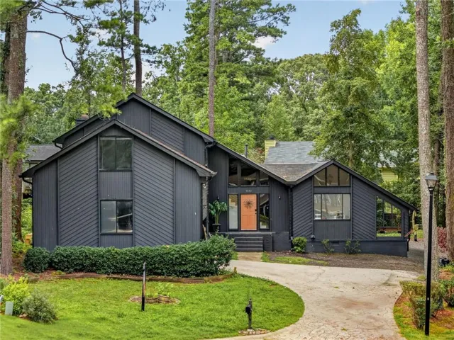 Contemporary architecture featuring a dark exterior, multiple gables, extensive window placement, and a curved driveway