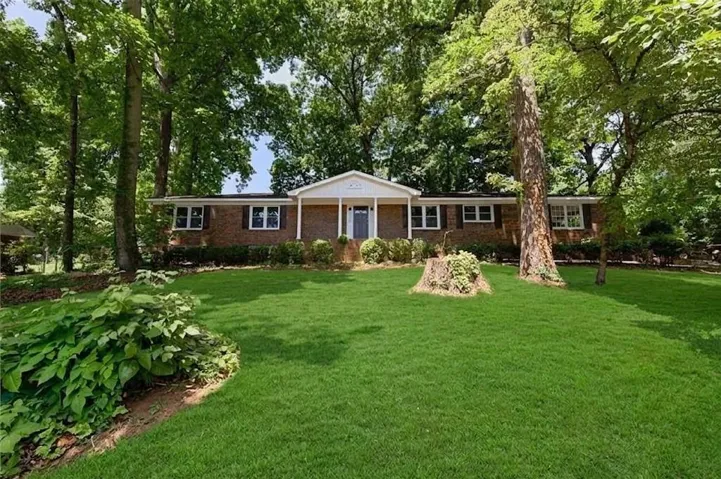 Brick exterior with a prominent front portico, complemented by a verdant front lawn and mature trees