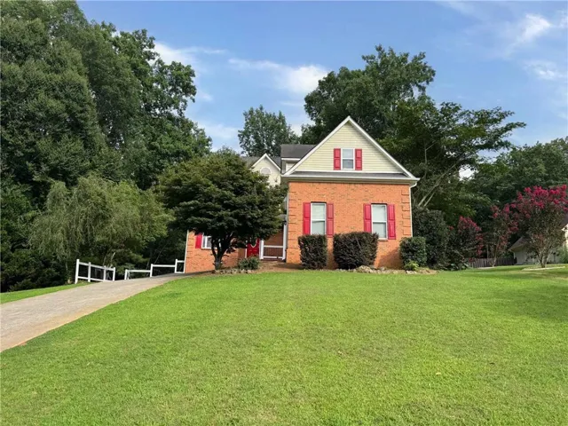 Brick exterior with a prominent gable, contrasting red window shutters, and a front entry door with sidelights