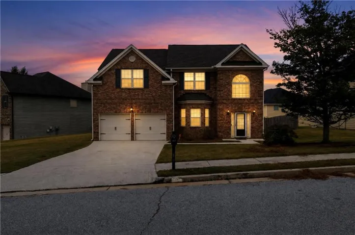 Brick exterior with a dark roof, two-car garage, concrete driveway, and a manicured lawn