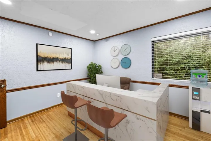 Reception area featuring a marble-finish counter with integrated accent lighting, wood-finish flooring, a window with blinds, and recessed lighting
