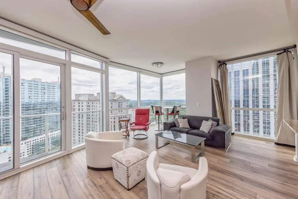 Living room featuring a wall of windows, light wood-type flooring, plenty of natural light, and a city view
