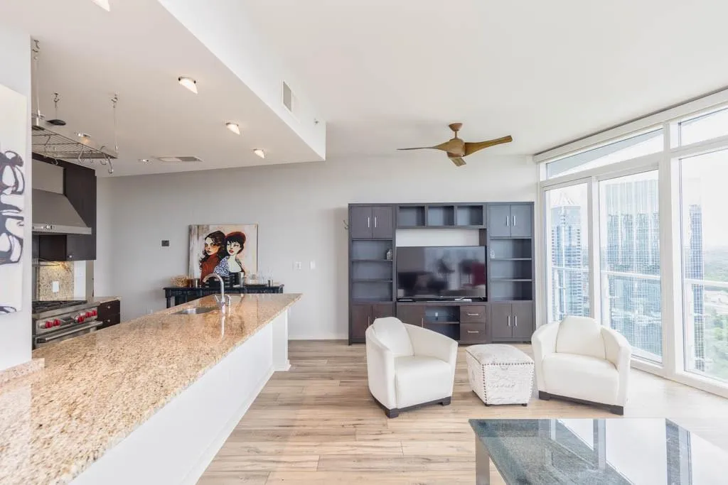 Living room featuring floor to ceiling windows, light wood-style flooring, and ceiling fan
