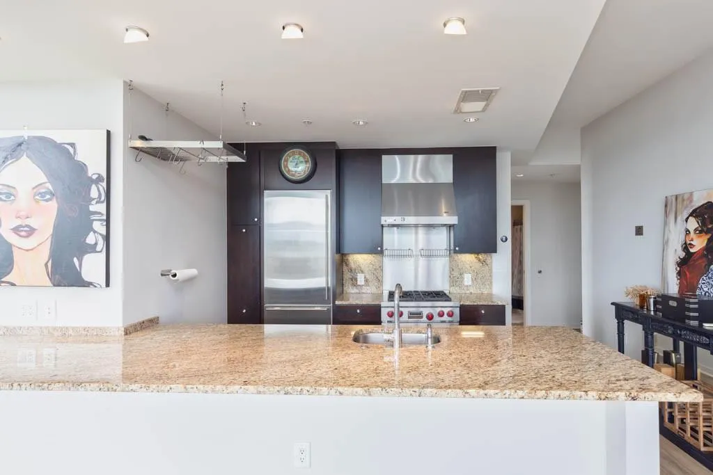 Kitchen with a peninsula, stainless steel built in fridge, light stone counters, and decorative backsplash
